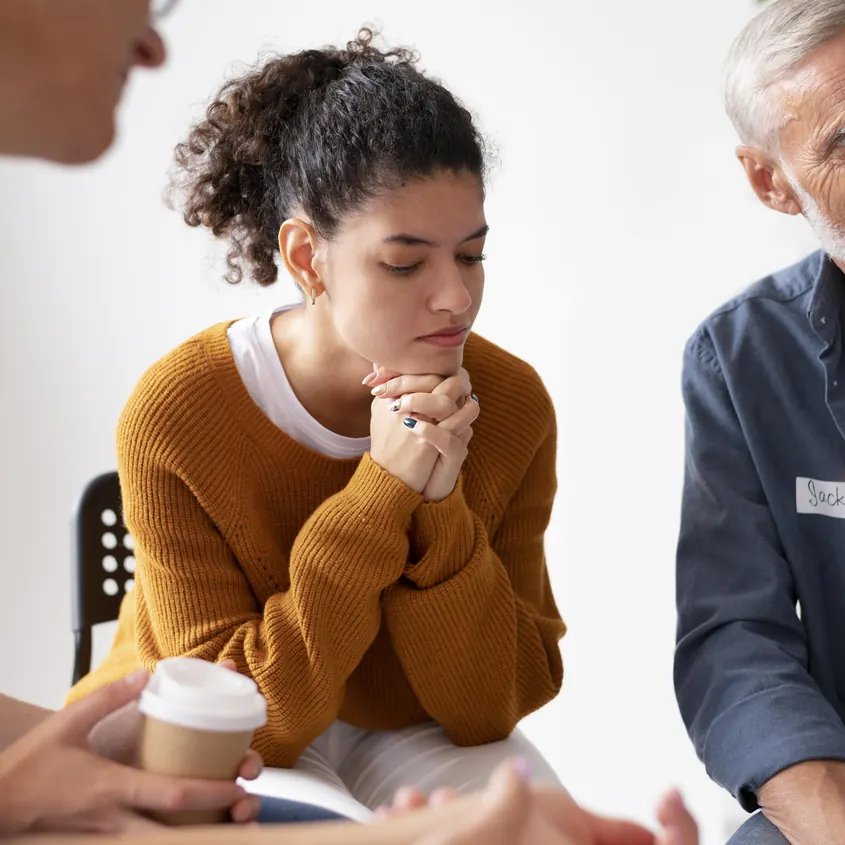 Woman listening during a group therapy session with peers and a counselor